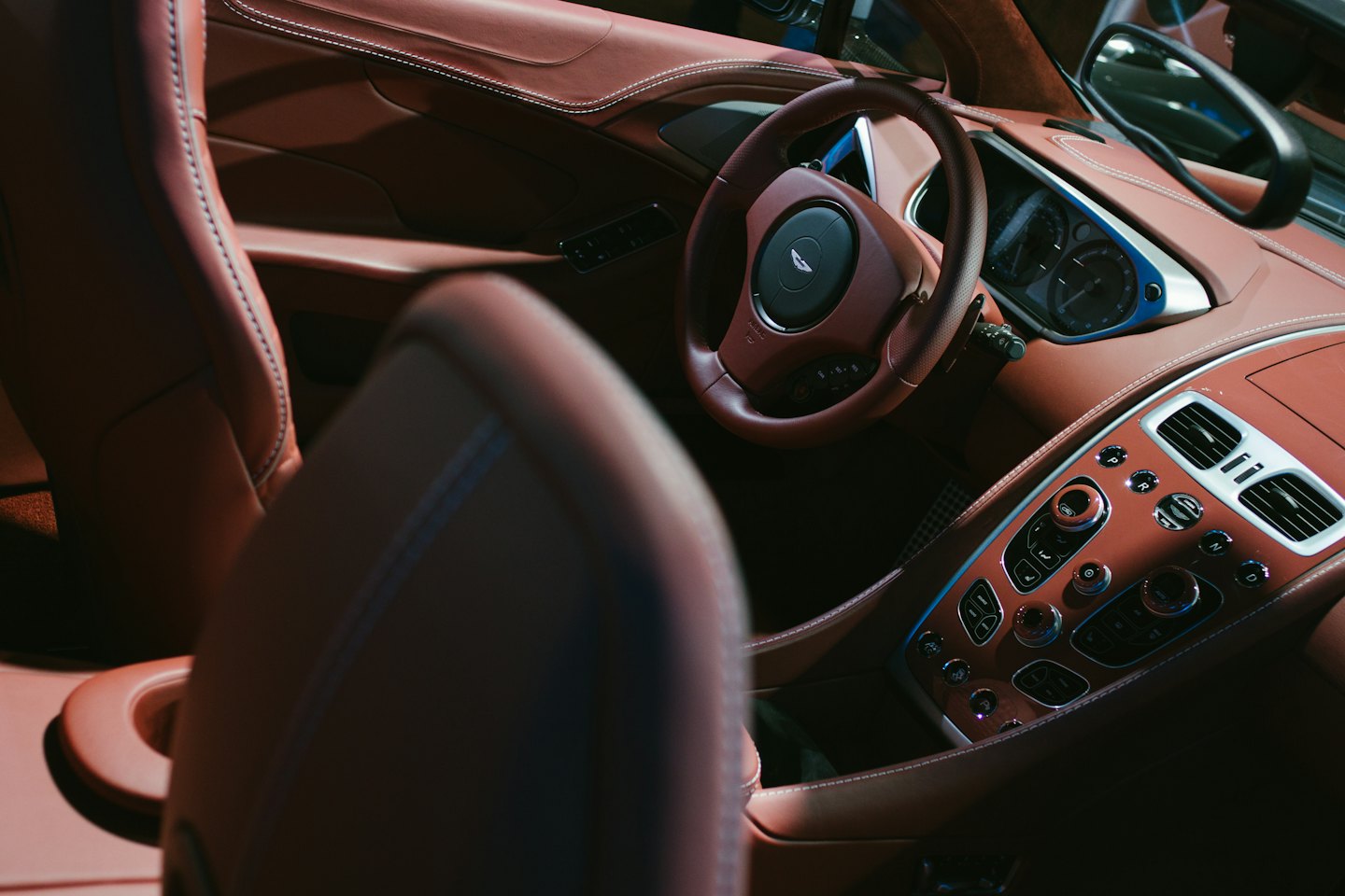 Bruin lederen auto-interieur met witte stiksels en zilveren accenten.